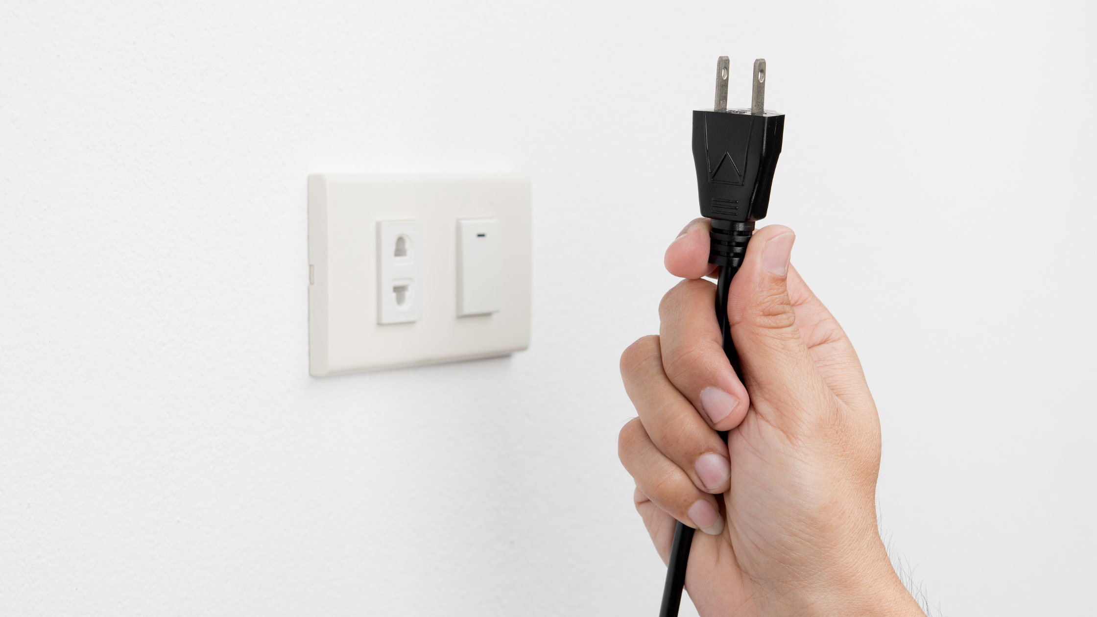 Person unplugging wall outlet to reduce EMF exposure